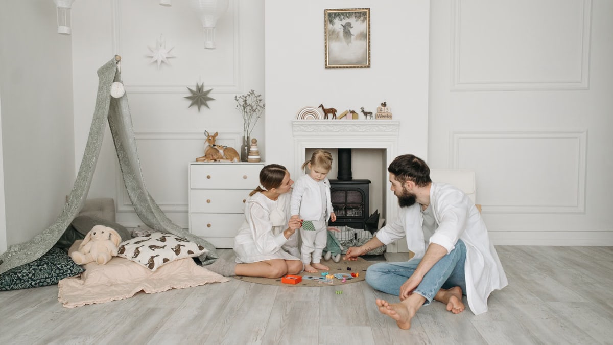 Warm family scene of parents playing with their daughter in a cozy white room.